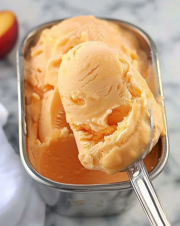 Bowl of refreshing easy peach sorbet with fresh peach slices on top.