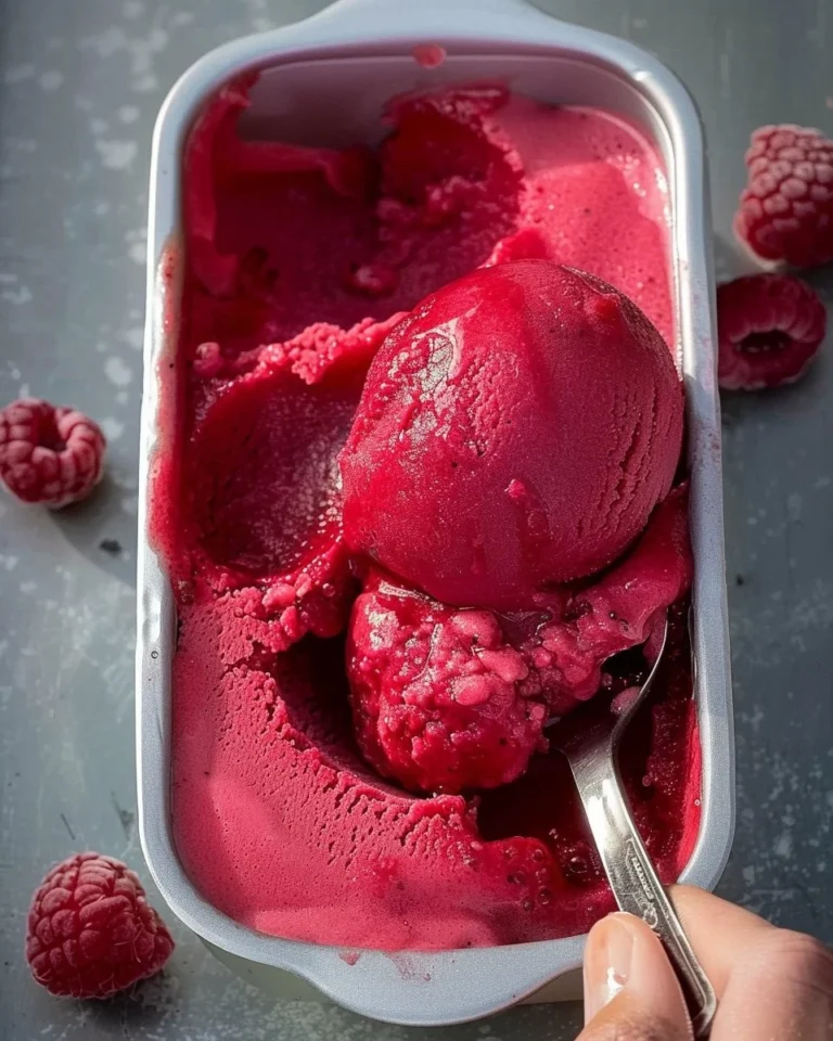 Delicious homemade Raspberry Sorbet in a bowl topped with fresh raspberries
